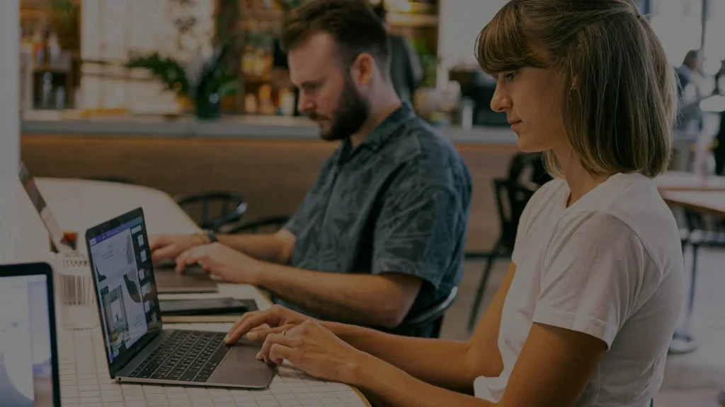Two people collaborating on laptops